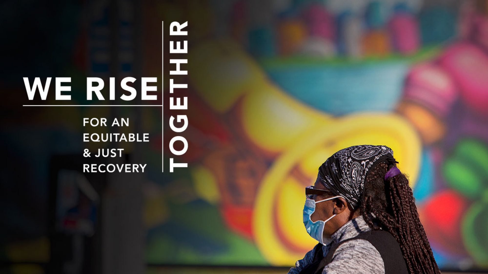Black woman, masked, in front of a colorful mural. Overlay text says We rise together for an equitable and just recovery.