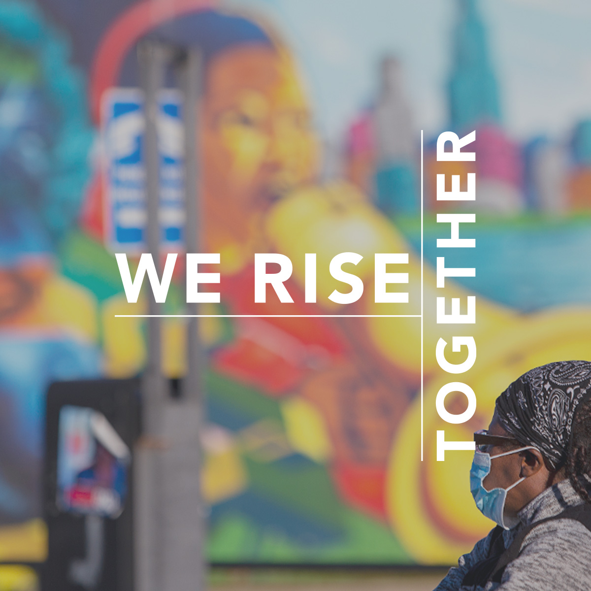 We rise together. Photo shows a black woman in a mask in front of a colorful mural.