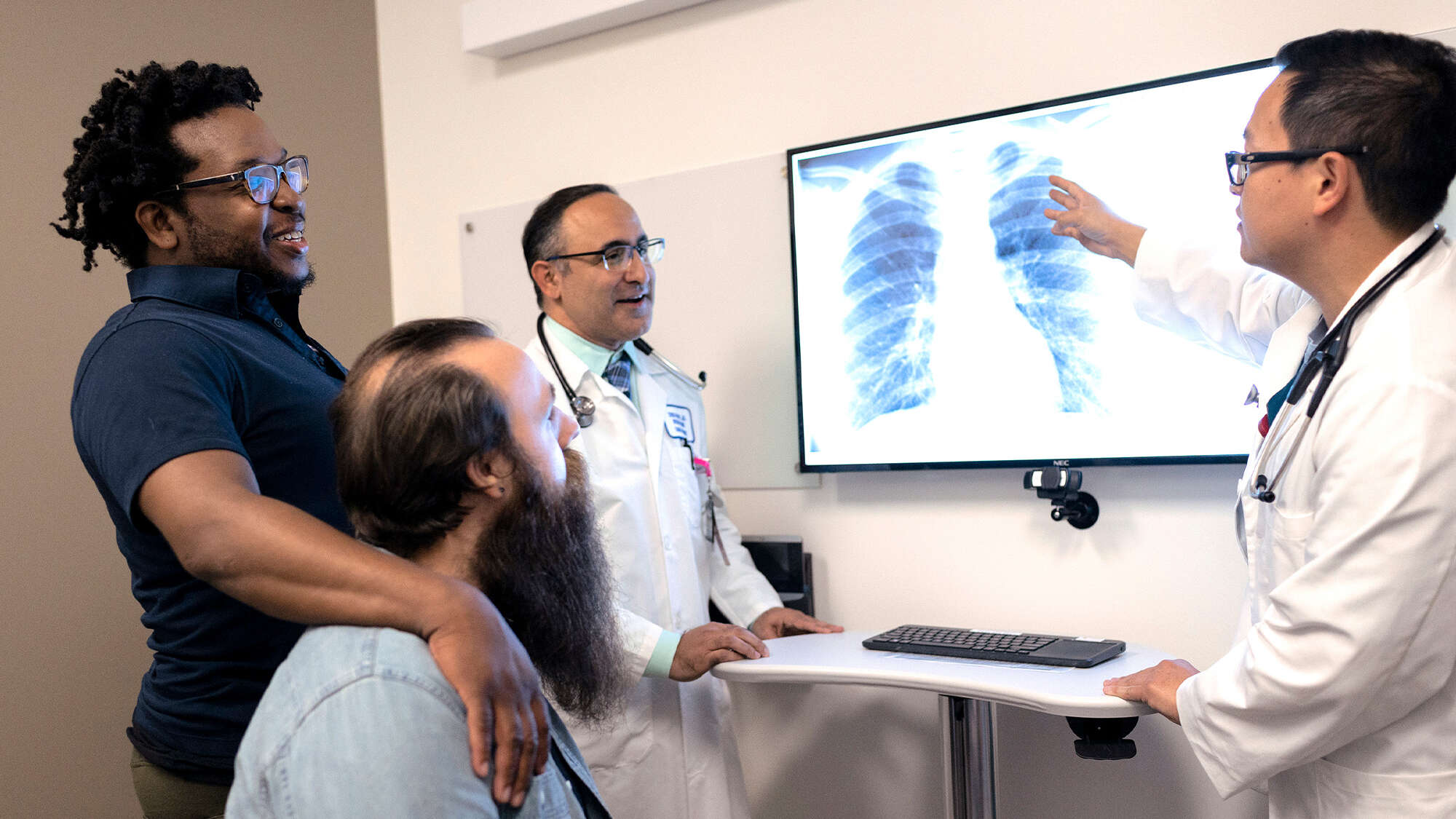 photo of 2 docs reviewing x-rays with male patient and his partner